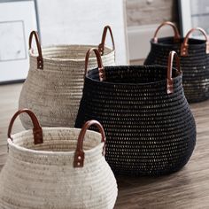 three baskets sitting on top of a wooden floor next to a framed photo in the background