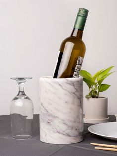 there is a wine bottle and two glasses in this marbled holder on the table