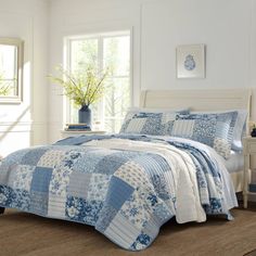 a blue and white quilted bed in a room with two chairs next to it