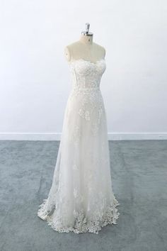 a white wedding dress on a mannequin in front of a white wall and floor