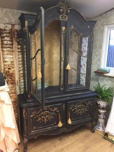 an antique china cabinet painted black and gold