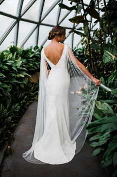 a woman in a white wedding dress holding a veil