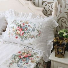 a white bed topped with lots of pillows next to a night stand and nightstands