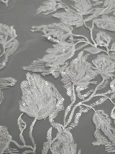 an embroidered fabric with flowers and leaves on grey background, close - up view from the bottom