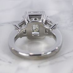 a close up view of a diamond ring on a marble surface with the center stone missing