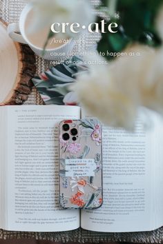 an open book sitting on top of a wooden table next to a vase with flowers