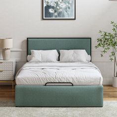 a bedroom with a bed, nightstand and plant in it