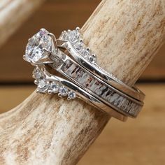 two wedding rings sitting on top of each other next to a piece of driftwood