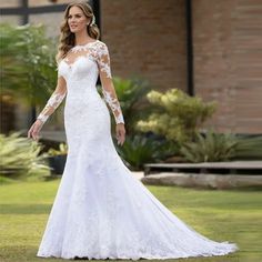 a woman in a white wedding dress standing on grass