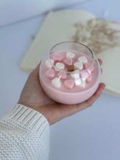 a hand holding a bowl filled with pink and white marshmallows