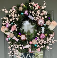 a christmas wreath with ornaments hanging on the front door