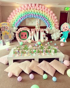 a table topped with lots of candy and balloons next to a giant balloon arch that says love