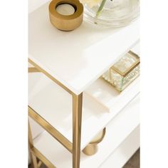 a white table with a glass bowl and some flowers on it, next to a gold candle holder