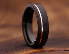 a black and gold wedding ring on top of a wooden table