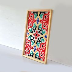 a wooden frame with a cross stitch pattern on the front and bottom, hanging on a wall