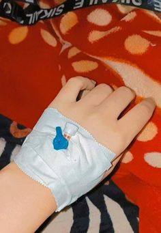 a child's hand with an arm cast on top of a red and white blanket