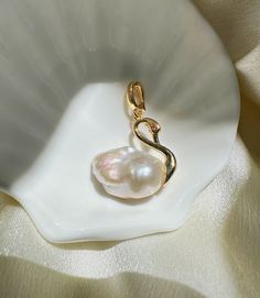 Capture the grace of a swan with our Gold / Silver Swan Pearl Necklace, a symbol of purity and refinement. This stunning piece features a lustrous natural pearl gracefully set in a golden swan design, perfect for elevating any outfit from ordinary to extraordinary. Comes with necklace chain. If you have a preferred style of necklace chain featured in one of the pictures, please leave us a note at checkout! Please message us to let us know if you want your swan pearl pendant to face a certain dir Swan Necklace Aesthetic, Ocean-inspired Gold Shell With Pearl Pendant, Elegant Gold Shell-shaped Pearl Necklace, Swan Locket, Swan Pendant Gold, Swan Design, Swan Jewelry, Gold Swan, Swan Pendant