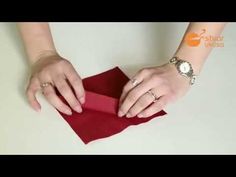 someone is folding the red paper on top of the other folded piece of cloth with their hands