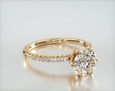 a yellow gold engagement ring with an oval cut diamond in the center and side stones on each band