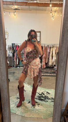 a woman taking a selfie in front of a mirror with her cowboy boots on