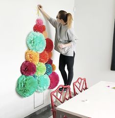 a woman is decorating a wall with pom - poms in an office