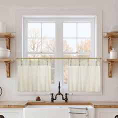 a kitchen with white walls and wooden shelves on either side of the window is an old fashioned dishwasher