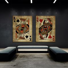 two framed playing cards on the wall in a room with black walls and grey couches