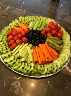 a platter filled with cucumbers, tomatoes and other vegetables