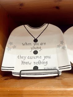 two white dishes with words on them sitting on a wooden shelf next to each other