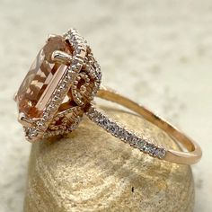 a fancy ring with an orange and white diamond in the center on top of a rock