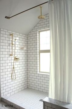 a white tiled bathroom with a window and shower