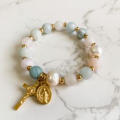 This decade rosary stretch bracelet is made with 8mm matte aquamarine and rose quartz gemstone beads, stretch cord, 10mm pearls, gold plated spacer beads and gold tone Italian made crucifix and Miraculous medal charms. The bracelet is 7 inches in length. Please send me an Etsy message if you need a different size. The bracelet will come packaged in a jewelry box to keep it safe on its journey to you. It's also perfect for gifting and would be a great addition to an Easter basket! Follow us on In Beads Packaging Ideas, Sacred Jewelry, Rosary Jewelry, Decade Rosary, Bracelets Design, Catholic Rosary, Catholic Jewelry, Rosary Bracelet, Rosary Catholic