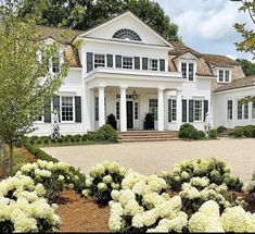 a large white house with lots of windows and bushes in front of the entrance to it