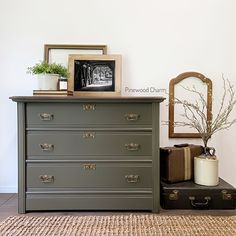 an old dresser is painted gray with gold trim and has a plant on top, along with other items from the collection