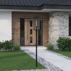 the front entrance to a house with grass and rocks around it, along with a lamp post