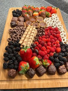 a wooden cutting board topped with chocolate covered strawberries and other fruit foodstuffs