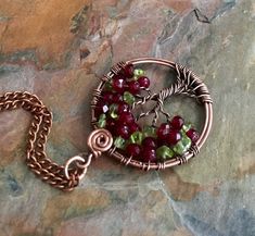 This unique & gorgeous wire wrapped Tree of Life pendant necklace. The pendant is made with deep red Garnet & Peridot gemstone using antiqued copper wires. The pendant measures about between 1.35 to 1.40 inch in diameter. It comes with your choice of an antiqued copper finished chain, Deerskin Lace leather or genuine black leather necklace Each pendant is handmade, so please allow slight variations from the shape of the branches and placement of the stones as shown. The Tree of Life is a Red Wire Wrapped Copper Jewelry, Red Copper Wire Wrapped Jewelry, Hand Wrapped Wire Necklaces For Gifts, Hand Wrapped Wire Necklace For Gift, Gift Necklace With Wire-wrapped Design, Red Copper Wire Jewelry Gift, Red Hand Wrapped Necklace As Gift, Hand Wrapped Red Necklace As Gift, Red Hand Wrapped Necklace For Gift