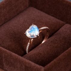 a ring with an opal stone in it sitting on a velvet cushioned box