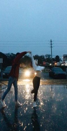 two people are dancing in the rain at night