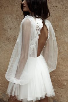 the back of a white dress with sheer sleeves