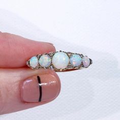 "This Victorian ring was handcrafted in England around 1900. It's a glimmery little stunner featuring five round cabochon opals patterned with 10 rose cut diamonds. The largest opal can be found at the center of the ring face, it measures 5.3 mm in diameter and 3.3 mm in depth. This piece is a size 8.25 and it weighs 4.5 grams. The ring face measures 7.5 x 22.5 and it sits 5.4 mm off the finger. It bears the gold purity mark, \"18 C\". Opals look like the universe and all her colors inside one t Victorian Style Opal Round Rings, Victorian Style Round Opal Ring, Victorian Round Opal Ring Hallmarked, Victorian Hallmarked Opal Ring, Opal Ring With Rose Cut Diamonds For Anniversary, Anniversary Opal Ring With Rose Cut Diamonds, Antique Hallmarked Opal Ring, Antique Style Round Opal Ring, Opal Jewelry With Rose Cut Diamonds