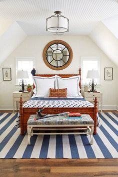 a bedroom with a large bed and blue striped rugs on the wooden flooring