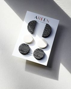 two black and white earrings on top of a card with the word arten written in it