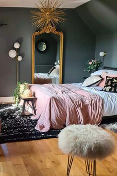 a bedroom decorated in pink and grey with a gold starburst mirror above the bed