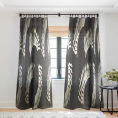 a bed sitting under a window next to a black and white blanket on top of a wooden floor