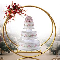 a wedding cake with pink and red flowers on top is surrounded by gold rings in front of a white background