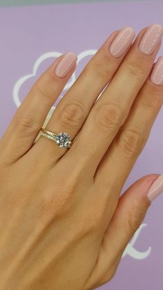 a woman's hand with pink manicured nails and an engagement ring