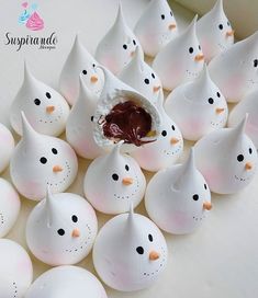 there are many small white eggs with chocolate in the shape of penguins on top of them