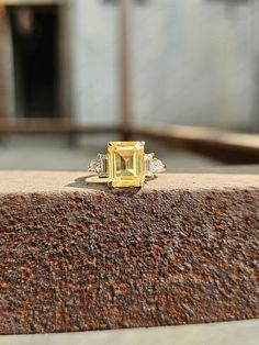 a yellow diamond ring sitting on top of a stone