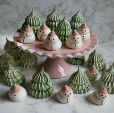 there are many small snowmen sitting on the cake platter with little shells around them